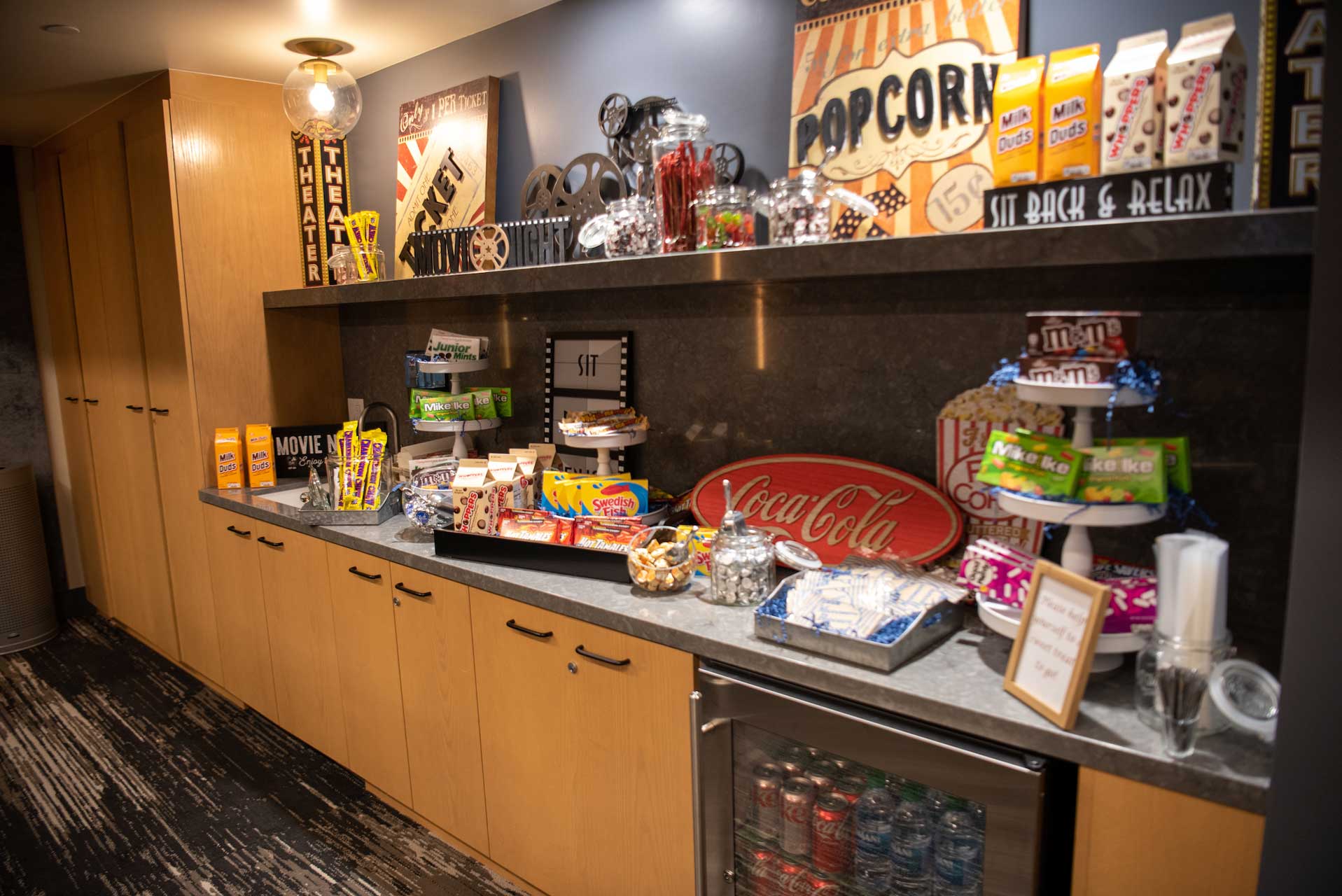 A countertop snack bar at MorningStar Senior Living Kirkland features movie-themed decor, displaying popcorn, candy, soda, and snacks. Bright boxes and containers are neatly arranged for residents to enjoy in this Retirement Living setting.