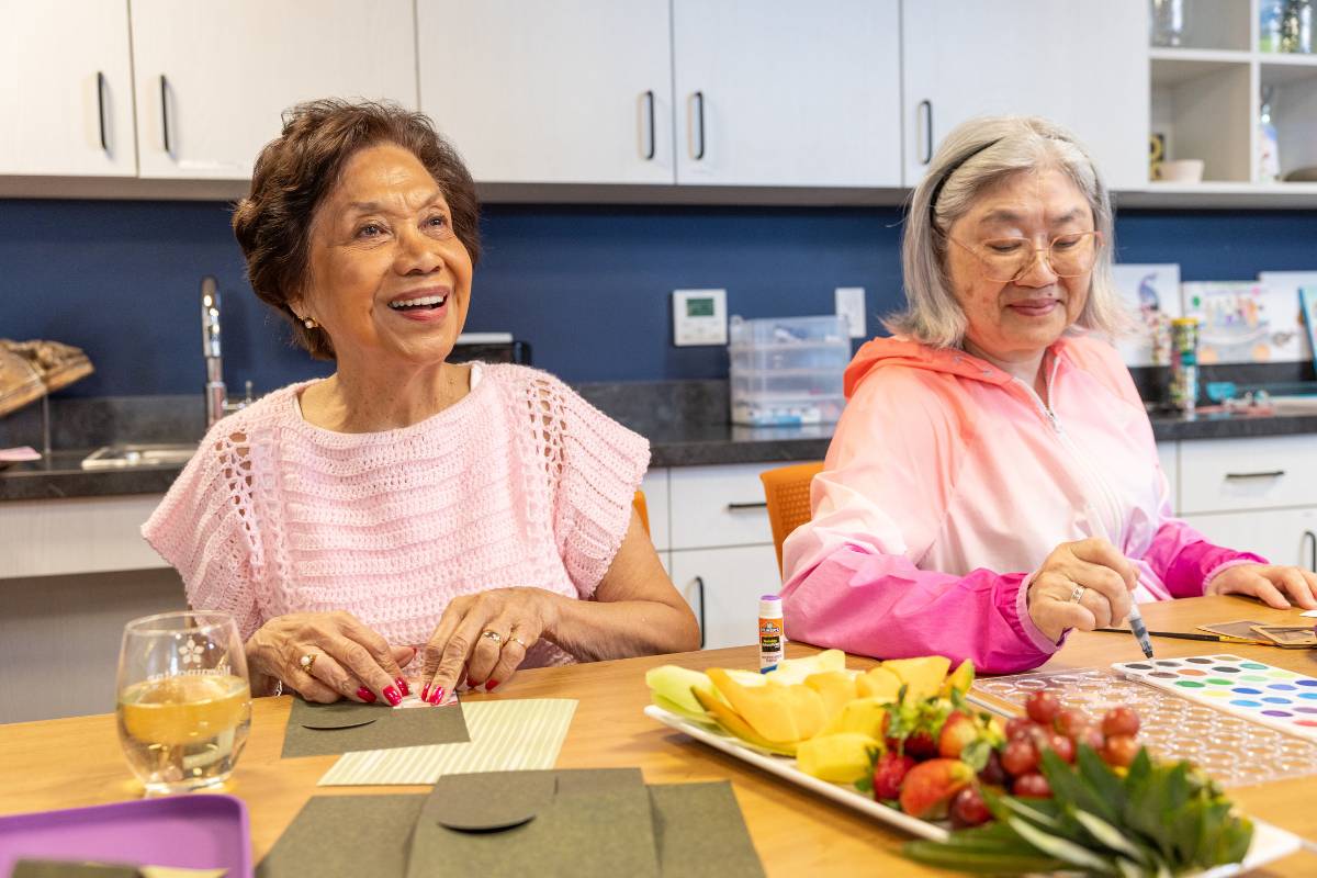 Two senior women smiling while crafting