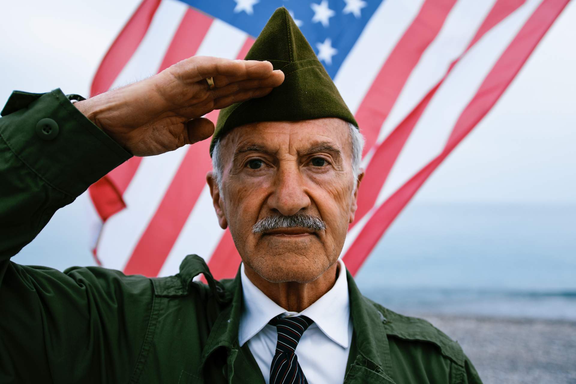 Senior man in uniform saluting in front of the American flag